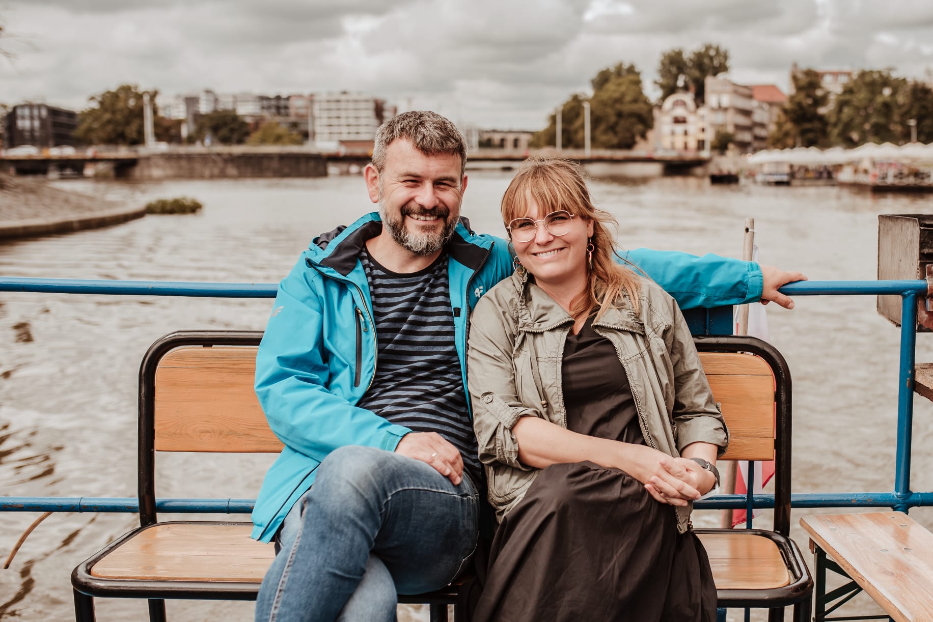 Współzałożyciele Fundacji, Katarzyna i Wojciech Stachura, siedzą razem na ławce na pokładzie łodzi, uśmiechając się do aparatu.